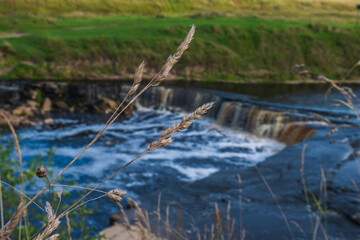 Waterfall, water flowing from the river falls down. A stormy river with a brown hue.