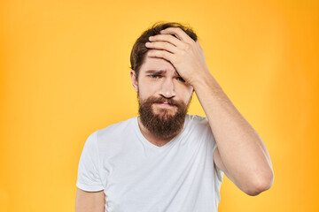 A man in a white t-shirt gestures with his hands studio lifestyle yellow background emotions