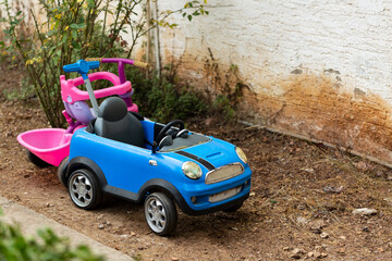 A yard with two children's toys in it. Big old toy car in summer garden, outdoors. Garden toys