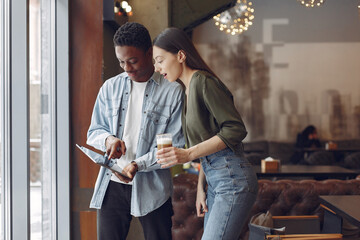 Students create a new project. Couple working in a cafe. International theme.