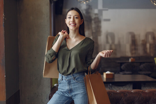 Beautiful girl in a cafe. Lady with shopping bags. Woman in a green shirt.