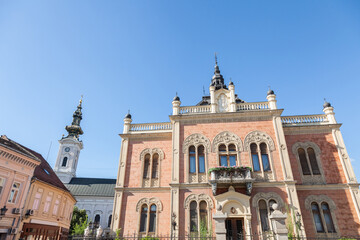 Fototapeta premium Facade of Vladicanski Dvor, the Bishop Episcopal palace of Novi Sad, Serbia, with its typical Austro hungarian architecture, with the Saborna crkva church, an Orthodox cathedral, in the background