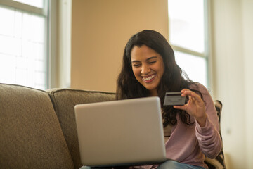 Fototapeta premium Young Hispanic woman shopping online at home.