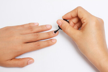 manicure applying, brushing fingernails with clear enamel, nail painting transparent nail polish on white background