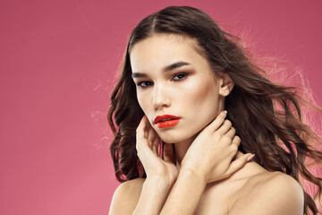 Naklejka premium Beautiful brunette woman with makeup on her face on a pink background naked shoulders