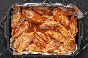 Raw chicken wings in a marinade on foil grill ready for cooking. Foil pack dinners. Top view