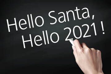 Hand holding a chalk and writing hello santa and hello 2021.