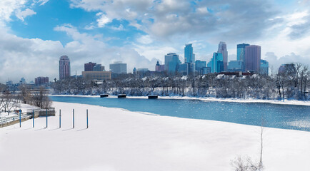 Downtown Minneapolis Winter View From Boom Island Park and Mississippi River with cloudy blue sky...