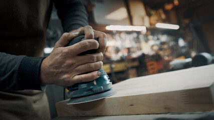 A carpenter grinds a piece of wood for a loft-style chair. Close up.