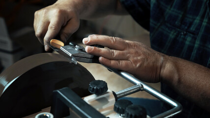 Man sharpens knives on a grinder. Close up hand