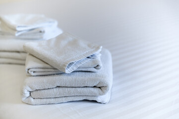 Stack of clean towels on bed in Hotel.