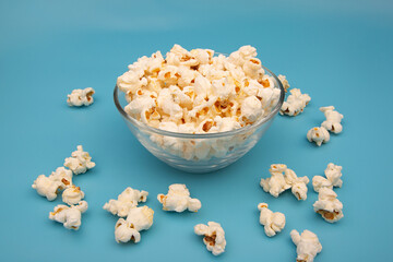 Glass bowl with popcorn on blue background