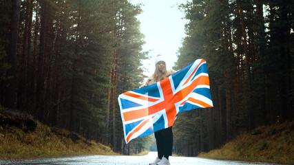 Girl holds the flag of United Kingdom in hands on the road