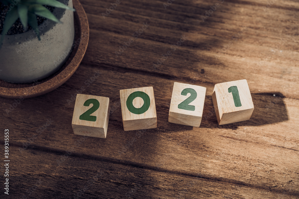 Poster 2021 happy new year on wood block on wood table and concrete wall with sunlight from window.hope new
