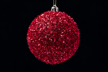 Close-up view of shiny bright red Christmas ball hanging on black background. Beautiful celebration...