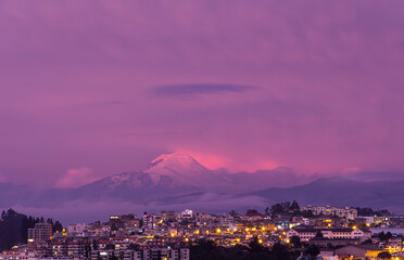 Cayambe volcano at sunset with Quito city aerial cityscape, Ecuador.