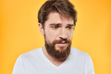Fototapeta premium Man with emotional expression white t-shirt close-up studio yellow background