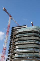 Modern Residential office building construction site and cranes during a vibrant day with blue sky.