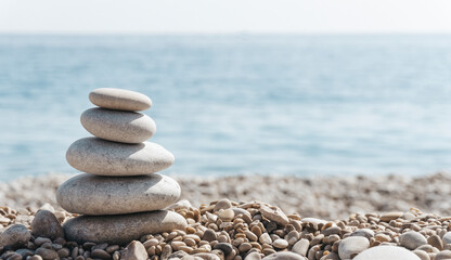 Zen relax background. A pyramid of stones on the beach in clear sunny weather. Background for meditation, yoga and massage