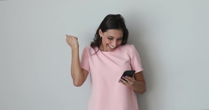Emotional millennial happy mixed race indian arabic ethnicity woman reading message on smartphone with good news, excited by getting shopping promo discount code or celebrating success lottery win.
