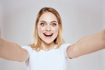 Cheerful blonde woman in white t-shirt cropped view light background