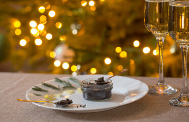 black caviar  and  glass of champagne on background christmas tree