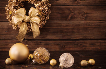 Christmas golden balls and wreath on dark wooden background