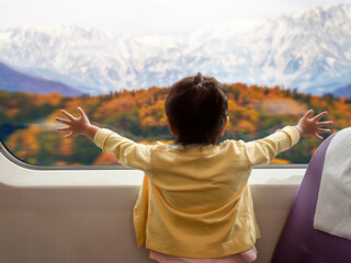Soft Focus of Happy and Excited Kids Traveling by Train with her Family during Autumn and Winter Season. a Girl Looking through Wide Glass Window. Moutain with Snow as Outside View