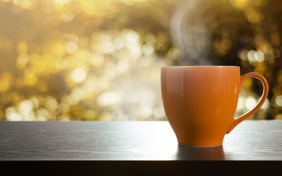 Cup of Hot Coffee on Table. Relaxation Concept. Side View. Golden bokeh as background