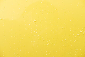 Close up shot of glossy yellow car paint surface. With drop of water and light ambient. Background...