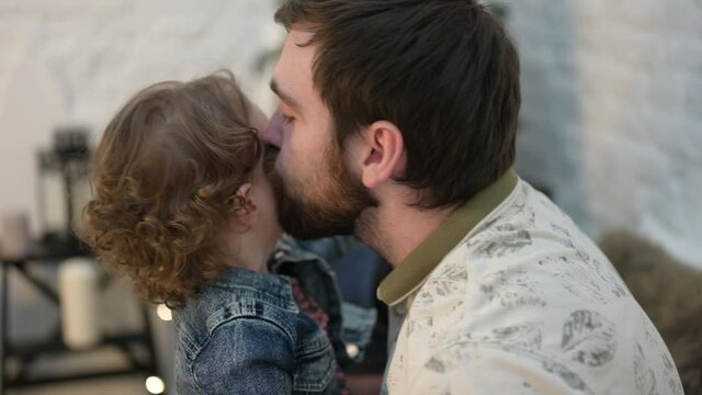 domestic lifestyle concept of happy family bearded male kissing his little child with wife girl near
