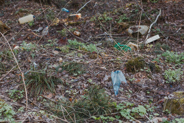 Garbage dump buried in the ground in the forest. Used dirty waste plastic bags, carton paper, old...