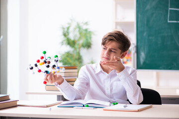 Schoolboy holding molecular model in the classroom