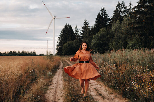 portrait of a Girl in a orange long dress with long hair in nature in the evening.