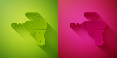 Paper cut Ray gun icon isolated on green and pink background. Laser weapon. Space blaster. Paper art style. Vector.