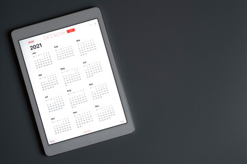 a tablet with an open calendar for 2021 year on a dark gray backgrounda tablet with an open calendar for 2021 year on a dark gray background. space for text