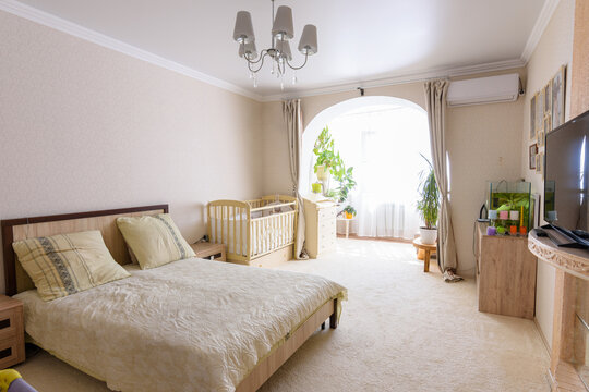 Nice interior of a bedroom combined with a balcony and a crib for a newborn baby
