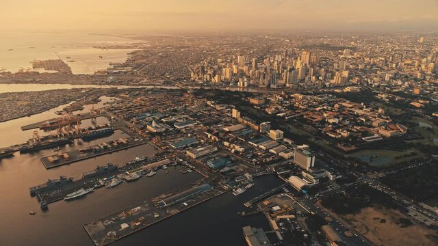 Sunrise over pier of metropolis city at sea bay aerial. Streets, roads at sun rise light in mist morning haze. Epic sunlight tropic cityscape of Manila capital town, Philippines. Cinematic drone shot