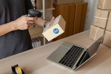Closeup warehouse service manager holding and scanning labels on boxes with barcode reader to...