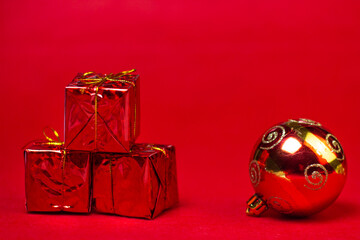 Christmas decorations on a red background. Holiday decorations. Three red gifts and a red Christmas ball on a red background. Christmas concept
