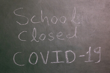 School Closed due to coronavirus notice on the green board written with chalk at the school.