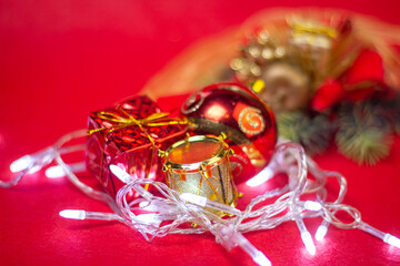Christmas decorations on a red background. Holiday decorations. A red Christmas ball, a red gift and a gold drum are in garland. Christmas concept