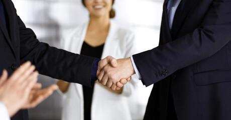 Unknown businesspeople are shaking their hands after signing a contract at meeting, close-up. Business communication concept