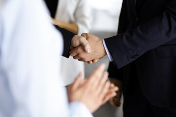 Fototapeta premium Unknown businesspeople are shaking their hands after signing a contract at meeting, close-up. Business communication concept