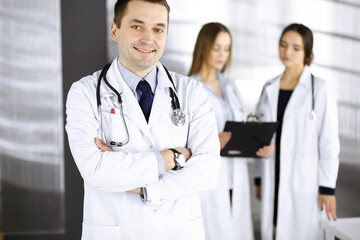 Fototapeta premium Professional middle aged doctor with a stethoscope and crossed arms at work in a clinic. Perfect medical service in a hospital. Medicine and healthcare concept