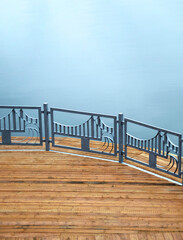 Fototapeta premium Pier with a boardwalk and a small fence on the background of blue water, top view.