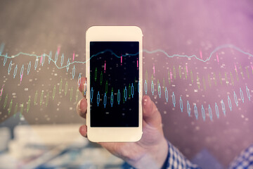 Double exposure of man's hands holding and using a digital device and forex graph drawing. Financial market concept.