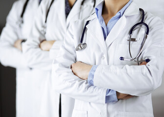 Group of modern doctors standing as a team with arms crossed in hospital office and ready to help patients. Medical help, insurance in health care, best disease treatment and medicine concept