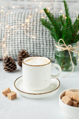 Cup of coffee, scarf and bouquet of fir tree branches. Cozy autumn or winter composition. Scandinavian style