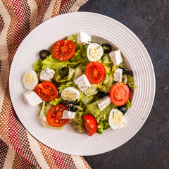Diet concept: vegetable salad with lettuce, tomatoes, quail eggs, olives and cheese.